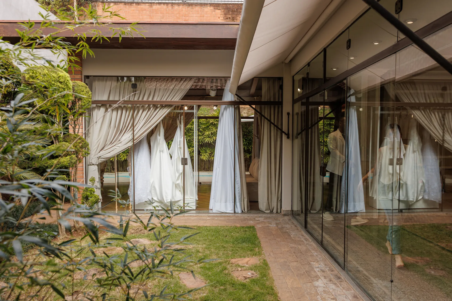 O jardim da Casa: pedras, bambus e as cortinas claras ao vento atrás do vidro.